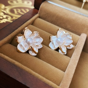 Elegant floral pearl stud earrings with white enamel petals in a luxury jewelry gift box