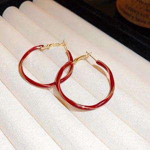 Detail of red enamel round hoop earrings with gold plating on a white jewelry tray