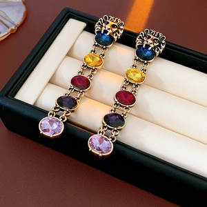 Boucles d'oreilles tête de lion vintage avec glands en strass colorés sur l'écrin