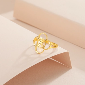 Detailed close-up of gold-plated stainless steel ring with interlocking circles on peach paper