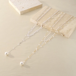 Detail of double-layer pearl necklace with Y-shape tassel on beige textured stone base