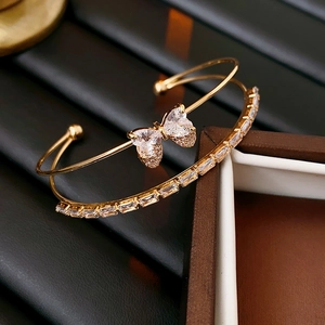 Macro shot of double-layer gold bow bangle with heart zircon stones on a dark background