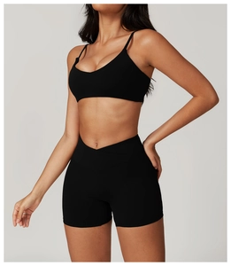 Detail of cross-waist design on black athletic shorts and professional yoga bra set