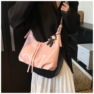 Pink matte leather hobo bag with vintage pleats and a black doll pendant on model