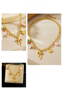Detail of gold chain necklace with cherry, mushroom, and heart charms on beige background