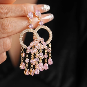 Detail of pink crystal teardrop tassel earrings in gold finish with dangling chains