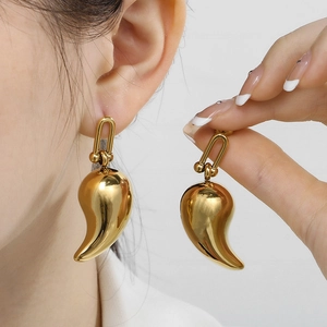 Détail de boucles d'oreilles goutte d'eau dorées portées par un mannequin pour l'éclat
