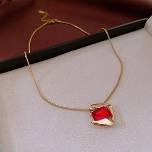 Close-up of golden stainless steel necklace with square red gemstone pendant detail
