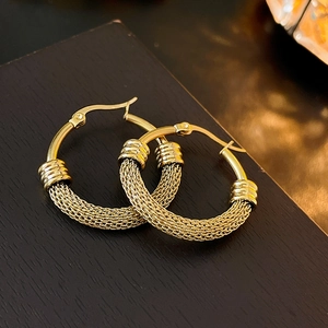 Macro detail of gold hoop earrings featuring a unique woven mesh texture and smooth clasp
