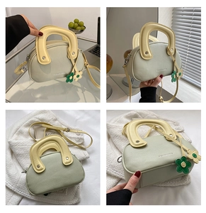 Détail du sac à main vert menthe avec poignée ronde jaune et breloques florales