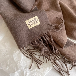 Detailed macro view of soft cashmere scarf with fringes and woven brand label