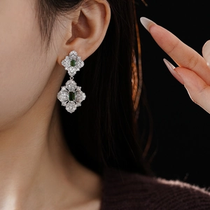 Close-up of vintage silver earrings with emerald square stone and white zircons on a model