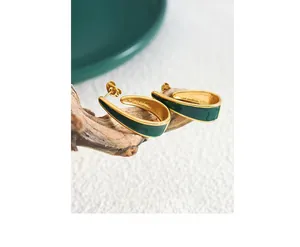 Detailed shot of vintage gold U-shaped earrings with dark green enamel on rustic wood