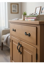 Detail shot of vintage black cast iron handle on a rustic wooden storage cabinet