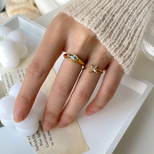 Detail of gold butterfly zircon rings on hand featuring marquise-cut stone and micro stones