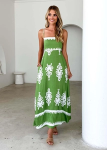 Detailed close-up of white floral embroidery on a green linen halter dress
