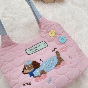 Primer plano del bolso acolchado rosa con bordado de cachorro y asas azules