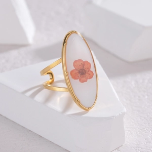 Detail of gold open ring featuring a real red dried flower preserved in clear resin