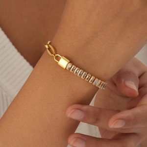Gold plated stainless steel chain bracelet with lock pendant and zircon stones on a model