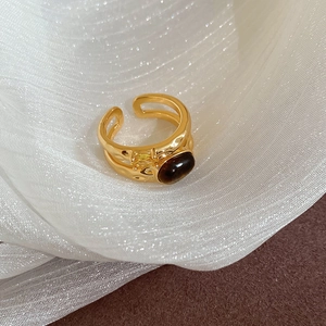 Detail view of a gold double-layer open ring with brown oval stone on white silk fabric