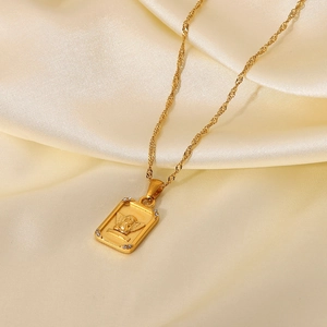 Close-up of 18K gold angel pendant necklace with crystal accents on silk background