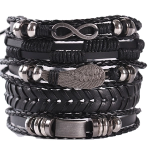 Detailed close-up of multilayer leather bracelet set with wing and infinity metal charms