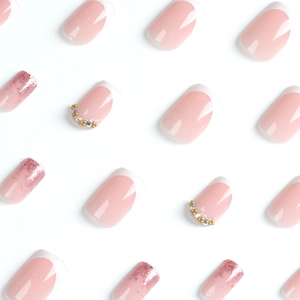 French tip nude pink press-on nails with white borders, pink glitter, and gold rhinestones