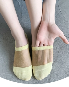 Close-up of sheer crystal silk socks with gold glitter mesh and yellow cotton trim on feet