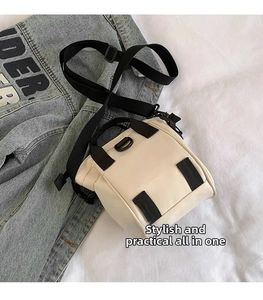 Détail du sac bandoulière en toile beige avec sangles noires sur denim