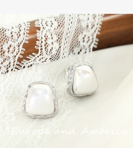Elegant pearl stud earrings with silver metal edges on a vintage lace background