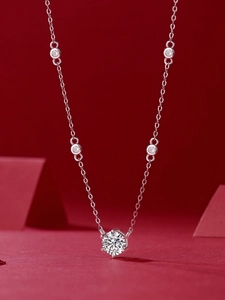 Macro detail of a 925 silver moissanite necklace with round cut stones on red backdrop