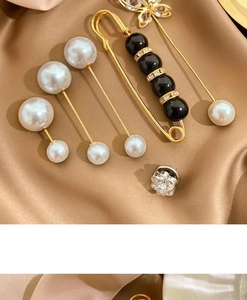 Detailed close-up of pearl and crystal brooches on elegant silk fabric background