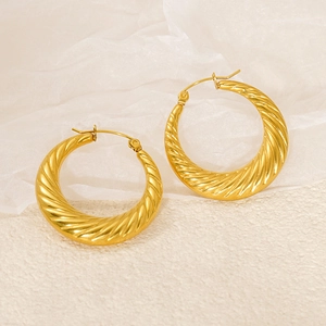 Macro detail showing twisted texture and polished gold finish on spiral hoop earrings
