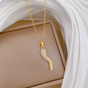 Elegant gold chili-shaped necklace with crystals and shiny rhinestones on a white fabric
