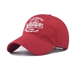 Detailed view of red cotton baseball cap featuring vintage white embroidery and textures