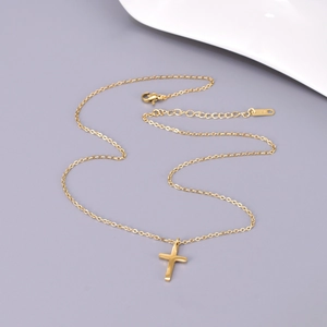 Collier avec pendentif croix en acier inoxydable plaqué or 18 carats sur fond épuré