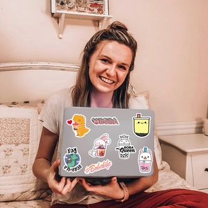 Woman holding laptop decorated with cute boba tea and animal waterproof stickers