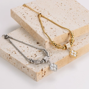 Gold and silver snake chain flower bracelets with mother-of-pearl charms on stone