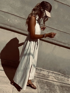 Elegant sleeveless white long dress made of breathable cotton with a stylish straw hat