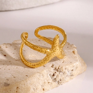 Detailed close-up of golden starfish ring with organic texture on natural stone