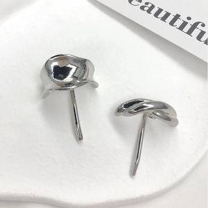 Macro view of silver asymmetric irregular abstract geometric stud earrings on stone