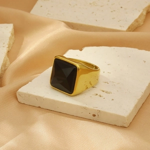 Macro detail of a vintage gold square ring with a large faceted black stone on stone texture