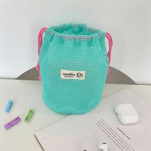 Macro shot of mint green mesh storage bag with pink drawstring and cartoon label