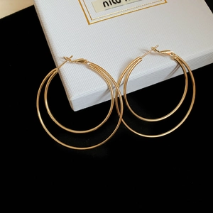 Close-up of golden double-layer hoop earrings resting on a white jewelry display box