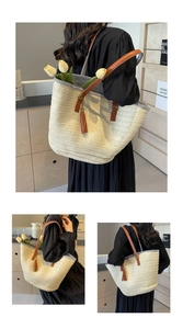 Close-up of woven straw tote bag featuring brown PU leather tassel and striped fabric lining