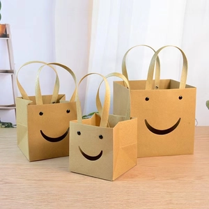 Three-piece smiley face kraft paper gift bags in various sizes on a wooden table