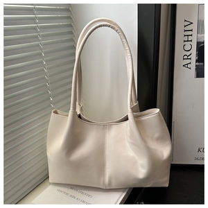 Detail view of cream-colored tote bag with textured faux leather and vertical stitching