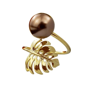 Elegant gold monstera leaf ring with a large lustrous brown shell pearl on white backdrop