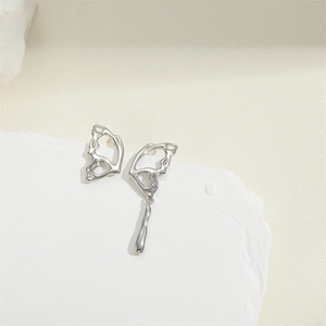 Detailed view of silver asymmetrical butterfly wing earrings on a white stone base