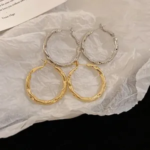 Minimalist irregular wavy hoop earrings in gold and silver finish with textured surface